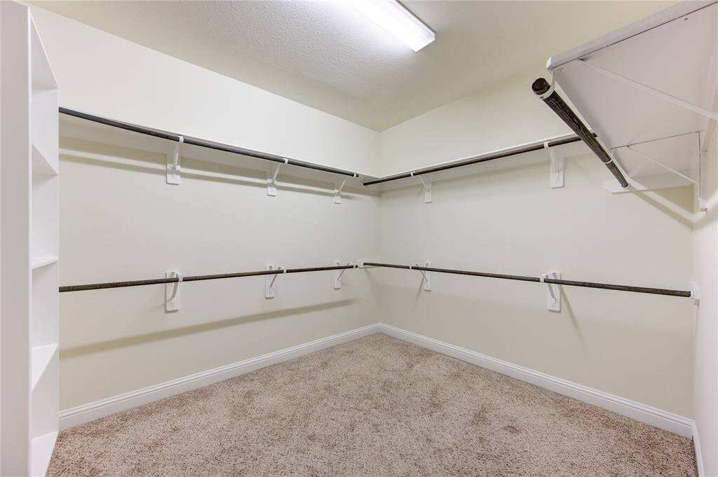 The master suite features a large walk-in closet with soft carpeting and freshly painted neutral-colored walls, creating a clean atmosphere.