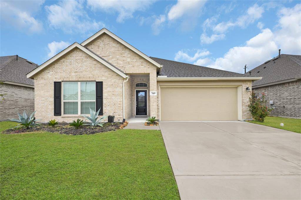 This is a charming, single-story brick home with a neatly landscaped front yard and a spacious two-car garage. The exterior features a welcoming entryway and modern windows.