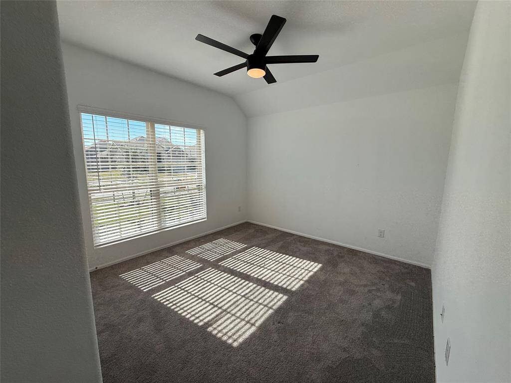 This room features a large window allowing plenty of natural light to fill the space. It has neutral walls, carpeted flooring, can be used as an office.