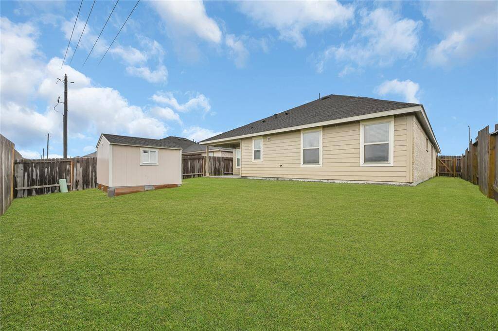 This photo features a spacious backyard with well-maintained grass and a small storage shed. The yard is enclosed with a wooden fence, providing privacy and security.