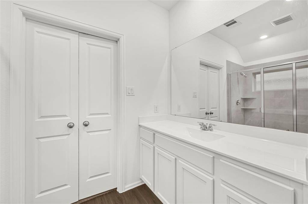 This bathroom features a modern design with a large vanity, sleek white cabinetry, and a spacious glass-enclosed shower. The neutral tones and ample lighting create a bright, inviting atmosphere.