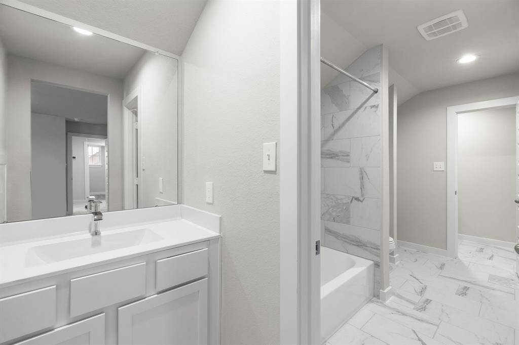 Experience convenience in the secondary bathroom, designed for Jack and Jill arrangements, now with a separate vanity area. This well-appointed space showcases stylish tile flooring, a bath/shower combo with an elegant tile surround, and light-stained wood cabinets. Sample photo of completed home with similar floor plan. As-built interior colors and selections may vary. Sample photo of completed home with similar floor plan. Actual colors and selections may vary.