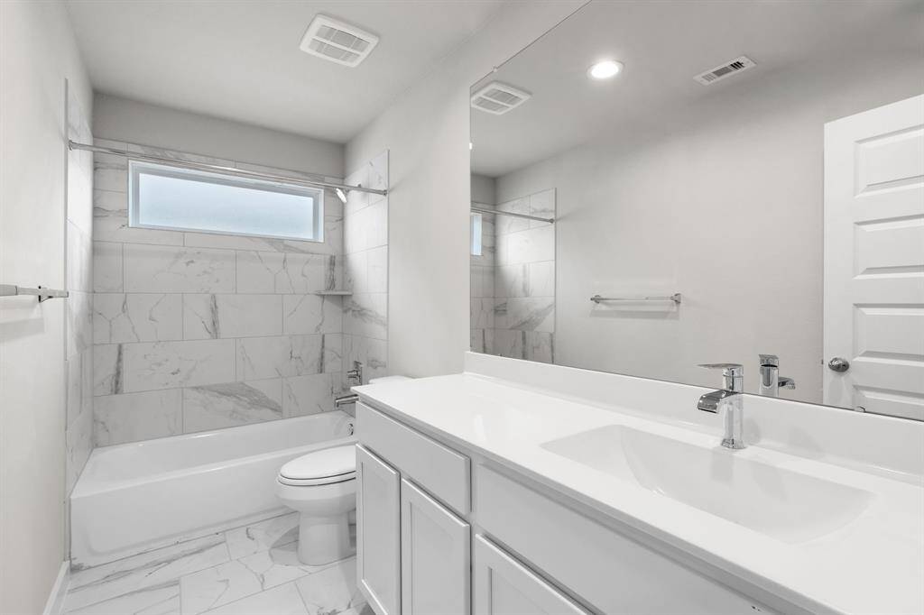 Indulge in refined charm in the secondary bathroom, where the tile flooring harmonizes with a bath/shower combo surrounded by tasteful tile. Light wood cabinets, coupled with a gorgeous countertop, elevate the space, cultivating a truly welcoming atmosphere. Sample photo of completed home with similar floor plan. As-built interior colors and selections may vary. Sample photo of completed home with similar floor plan. Actual colors and selections may vary.