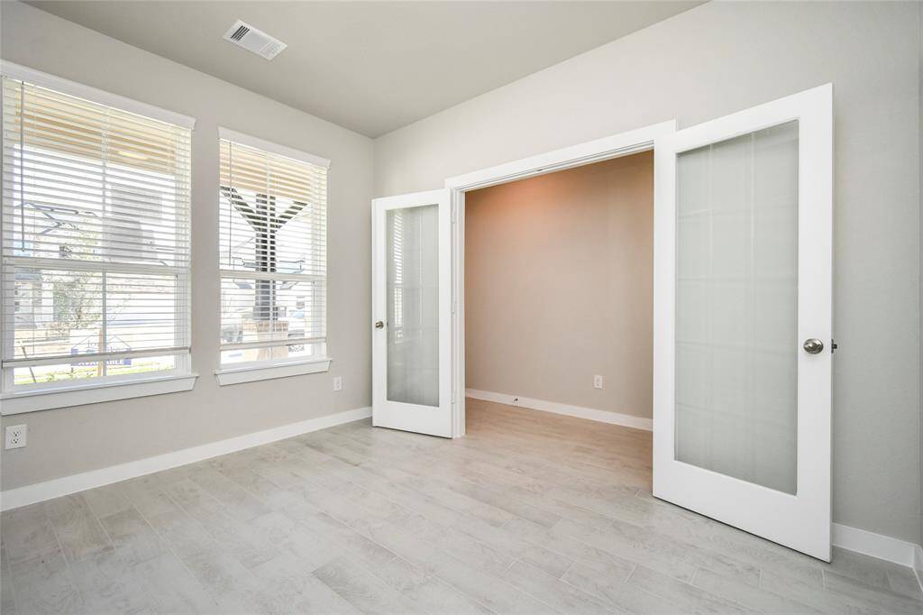At the forefront, a refined home office beckons productivity and focus. Luxurious details like tile flooring, custom paint, expansive windows with privacy blinds, and French doors create an inspiring workspace. Sample photo of completed home with similar floor plan. Actual colors and selections may vary.