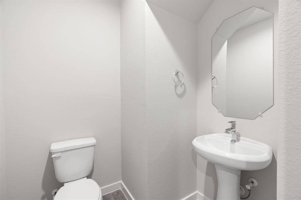 Immerse yourself in modern elegance within this delightful half bathroom. Featuring a sophisticated 5-panel door, upgraded pedestal sink, contemporary hardware. Sample photo of completed home with similar floor plan. Actual colors and selections may vary.