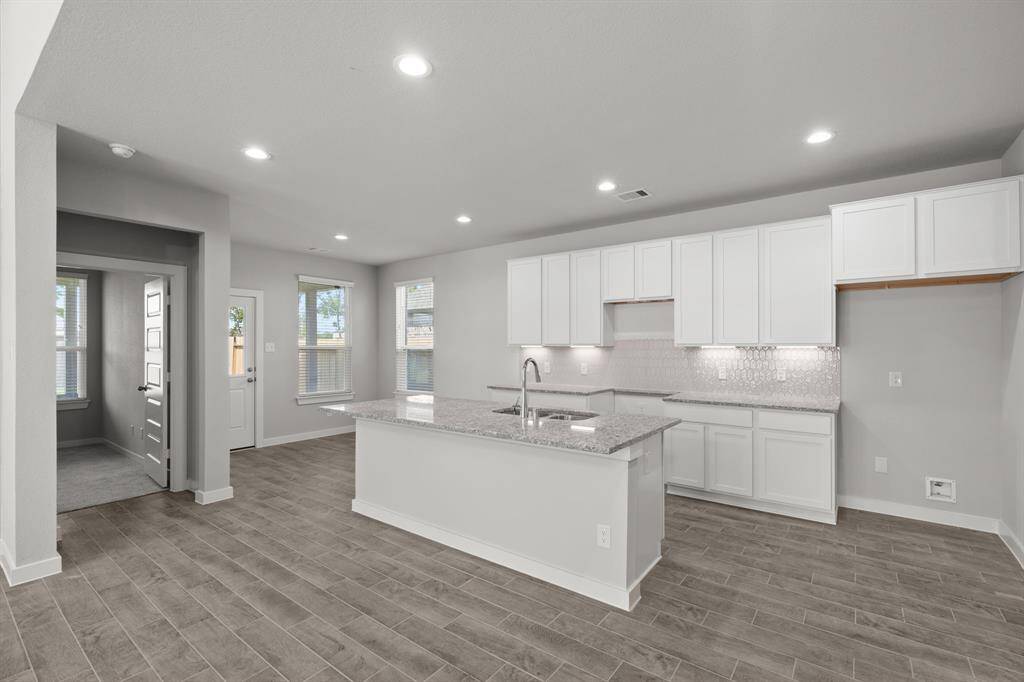 Experience the epitome of a dream kitchen in this generously spacious layout! Revel in features like a massive granite island, high ceilings, soft-close cabinets, granite countertops, stainless steel appliances, a sleek tile backsplash, and recessed lighting. The extended counter area provides additional functionality. With an open concept design, this kitchen seamlessly connects to the expansive family room, creating a perfect and inviting hub for gatherings.