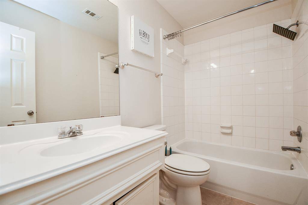 Bright and functional secondary bathroom featuring a sleek vanity and a classic tiled shower/tub combo.