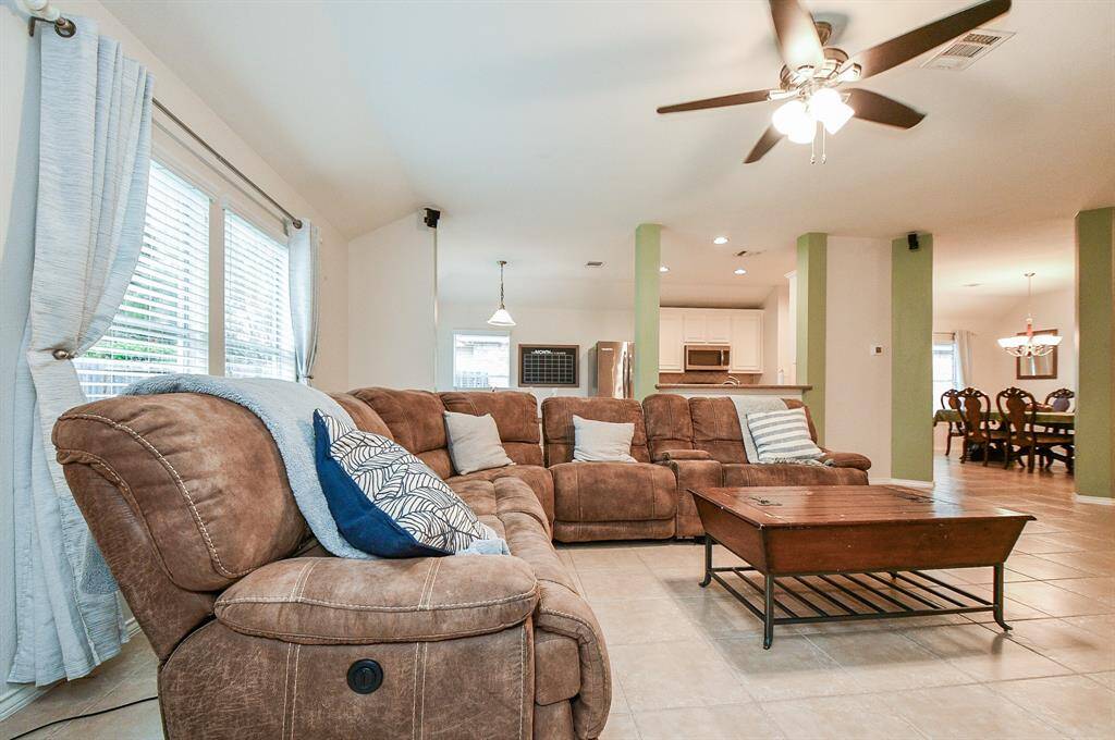 This spacious living room can accommodate a large sectional sofa. It opens to the kitchen and dining area, creating a seamless flow for entertaining. Large windows provide ample natural light.