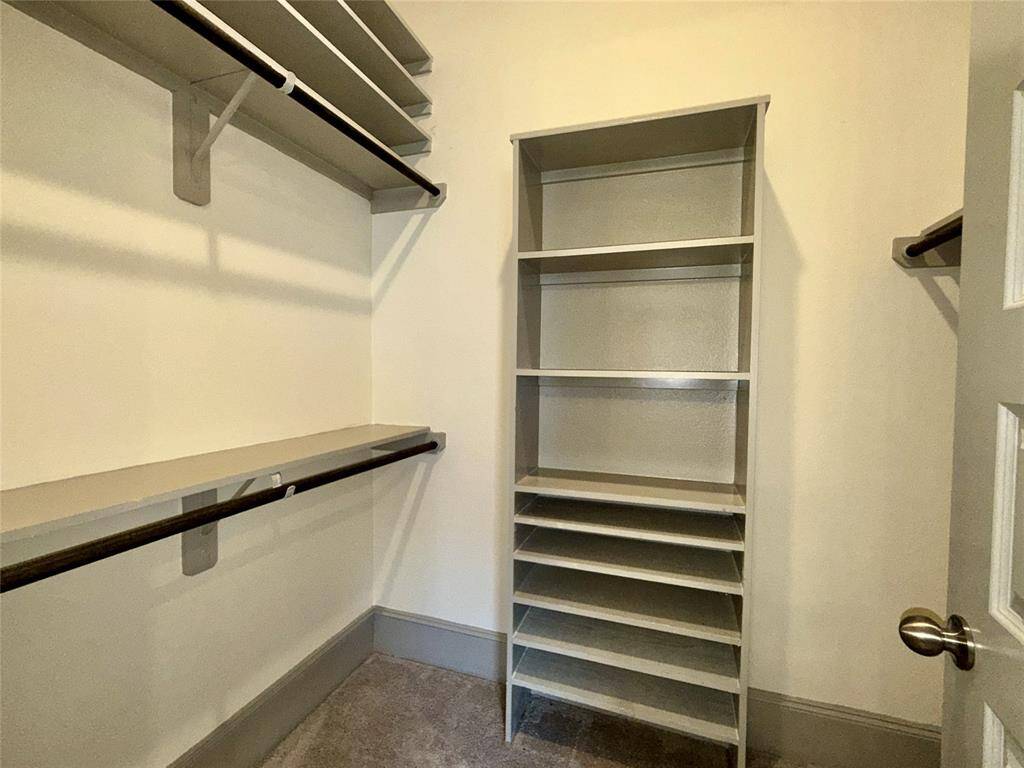 Well-organized walk-in closet featuring multiple shelves and hanging rods for ample storage space. The neutral tones provide a clean, modern look.