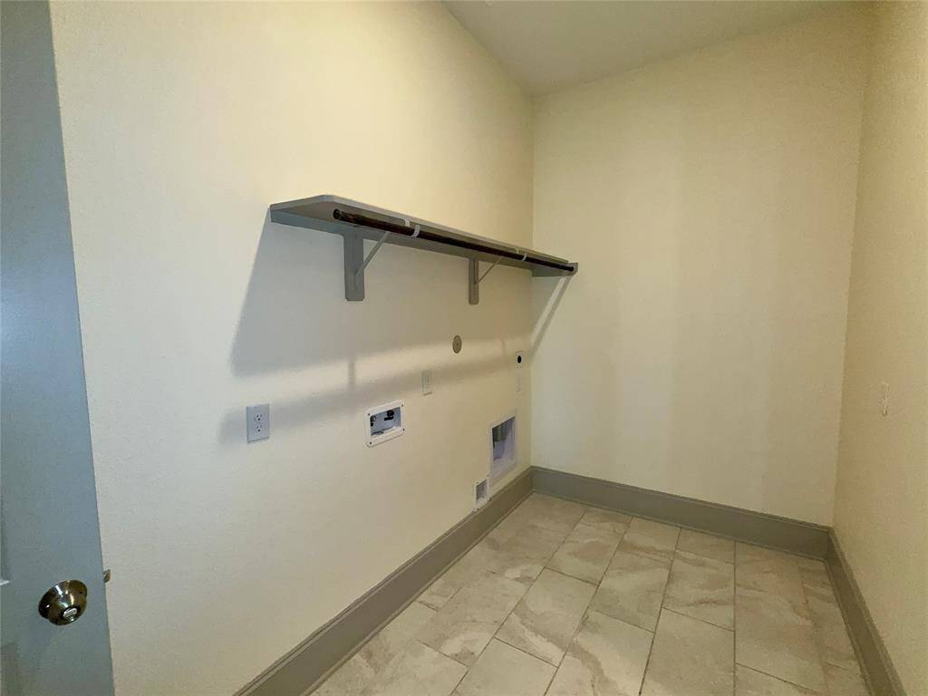 Laundry room with tiled flooring, plumbing and electrical hookups for a washer and dryer, and a shelf for storage.