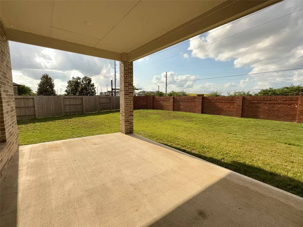 Scovered patio, featuring a mix of brick and wooden fencing, providing privacy and a great outdoor space for relaxation or entertaining.
