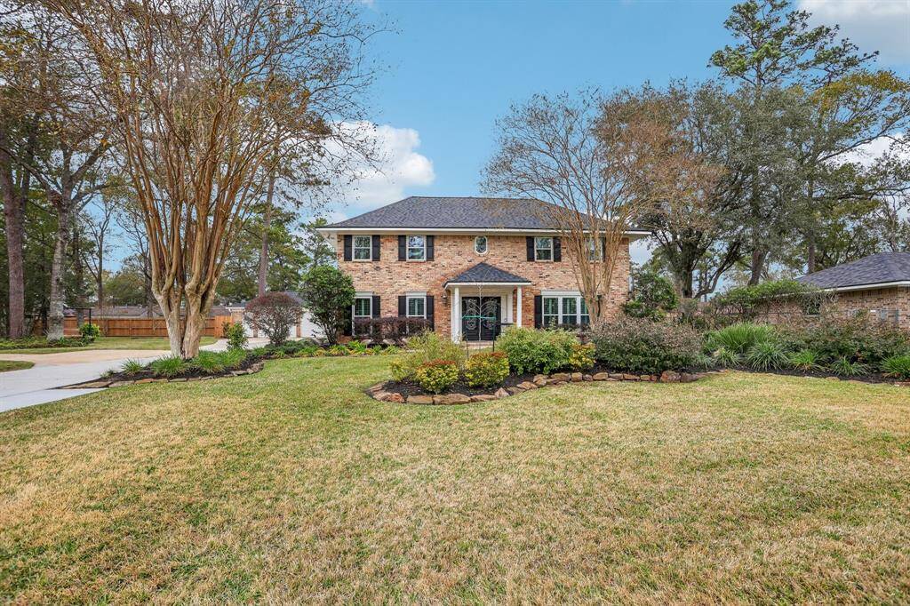 731 Cotter is a charming two-story brick home with a well-maintained front lawn and mature trees. The driveway leads to a spacious garage on the left, and the landscaping is neatly arranged with shrubs and flower beds, adding to the home's inviting curb appeal.