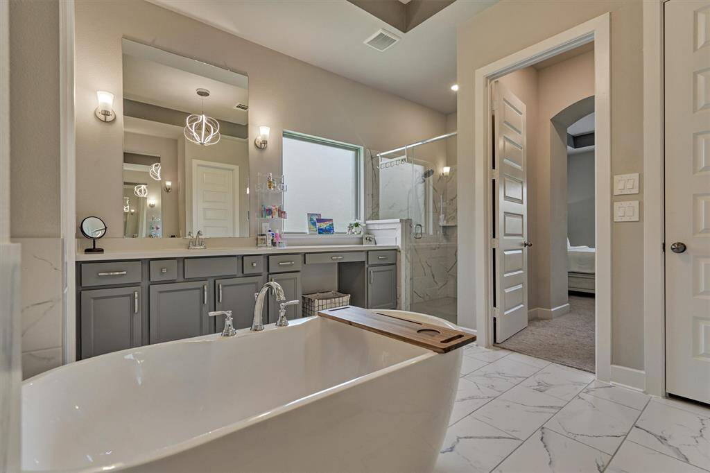The Primary Bath Offers Lots Of Cabinetry Storage, Quartz Counters, Vanity Sitting Space, Sconce Lights, His & Hers Walk-In Closets, A Soaker Tub, And An XL Walk-In Shower.