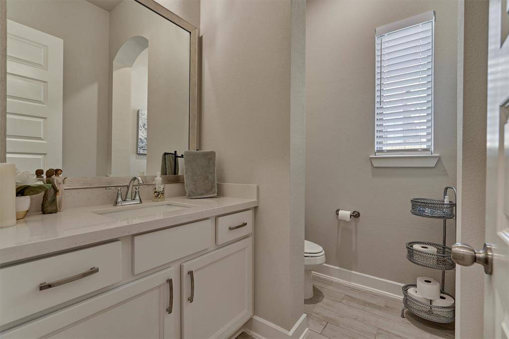A First Floor Powder Room Is Conveniently Situated For Guests And Family Alike.  Take Note Of The Large And Handsome Vanity (Shaker Cabinets, Quartz Counter, Pulls, Framed Mirror, And Under-Mount Sink).