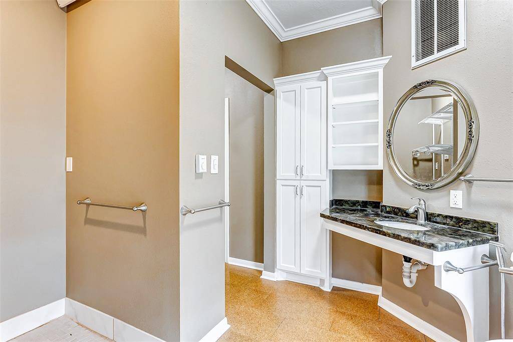 A beautifully designed vanity with custom cabinetry and a granite countertop adds charm and functionality to the primary bathroom.