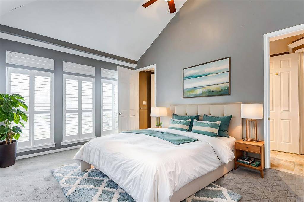 Spacious and bright, the primary bedroom features vaulted ceilings, plantation shutters, and a soothing color palette, creating a serene retreat.