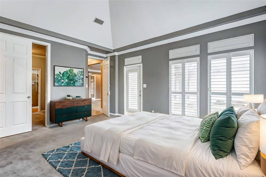 Natural light floods the primary suite through expansive windows, highlighting the room’s airy ambiance and timeless design.