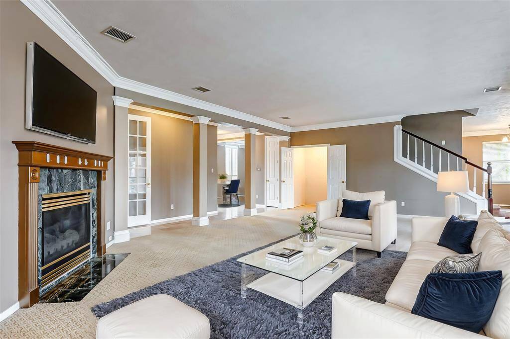The expansive living room combines elegance and comfort, featuring a classic fireplace, crown molding, and an open flow to adjoining spaces.