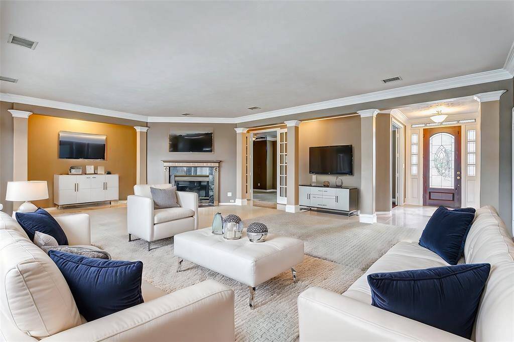A view of the inviting living room with its striking columns and access to the foyer sets the tone for a grand yet warm atmosphere.