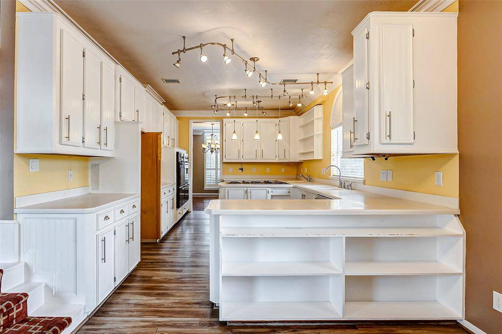 This bright kitchen boasts abundant cabinetry, expansive countertops, and modern track lighting, perfect for both everyday living and entertaining.