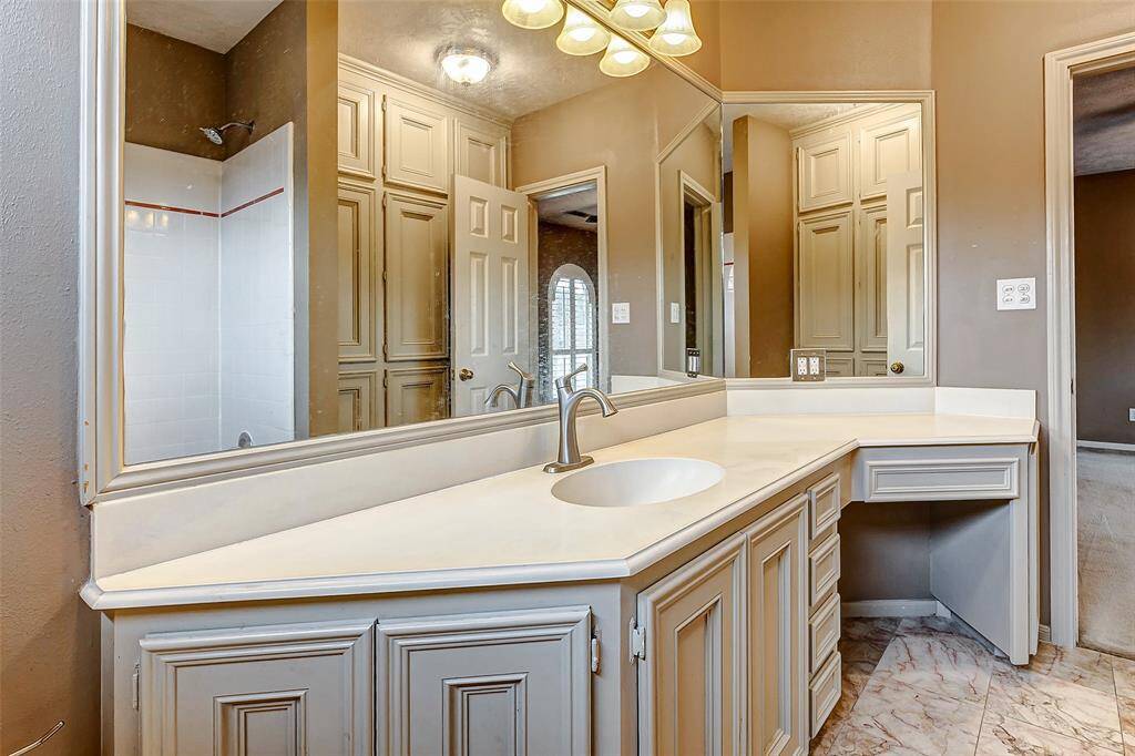 An expansive vanity with soft lighting, built-in storage, and a large mirror creates a serene space for daily pampering.