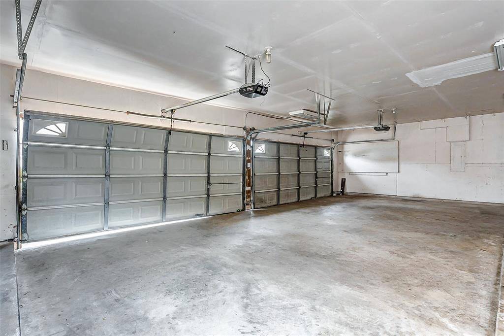 The oversized garage boasts ample room for multiple vehicles, storage, or a workshop. With pristine concrete flooring and functional shelving options, it’s the perfect space for both practicality and hobbies.