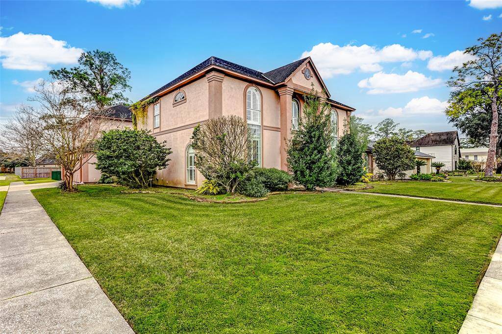 The side perspective of the property highlights its expansive footprint and manicured lawn. With well-placed trees and shrubs adding a touch of privacy, the home's design perfectly blends functionality with traditional charm.
