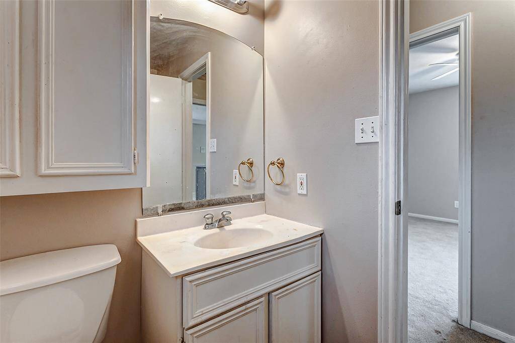 A cozy and functional bathroom with classic cabinetry and a well-lit vanity. This space provides convenience and privacy, perfect for guests or family use.