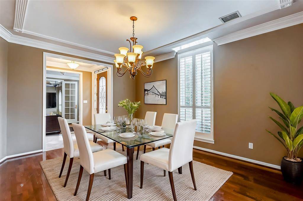 A sophisticated dining space with elegant crown molding, a statement chandelier, and gleaming hardwood floors—perfect for hosting dinners or family gatherings.