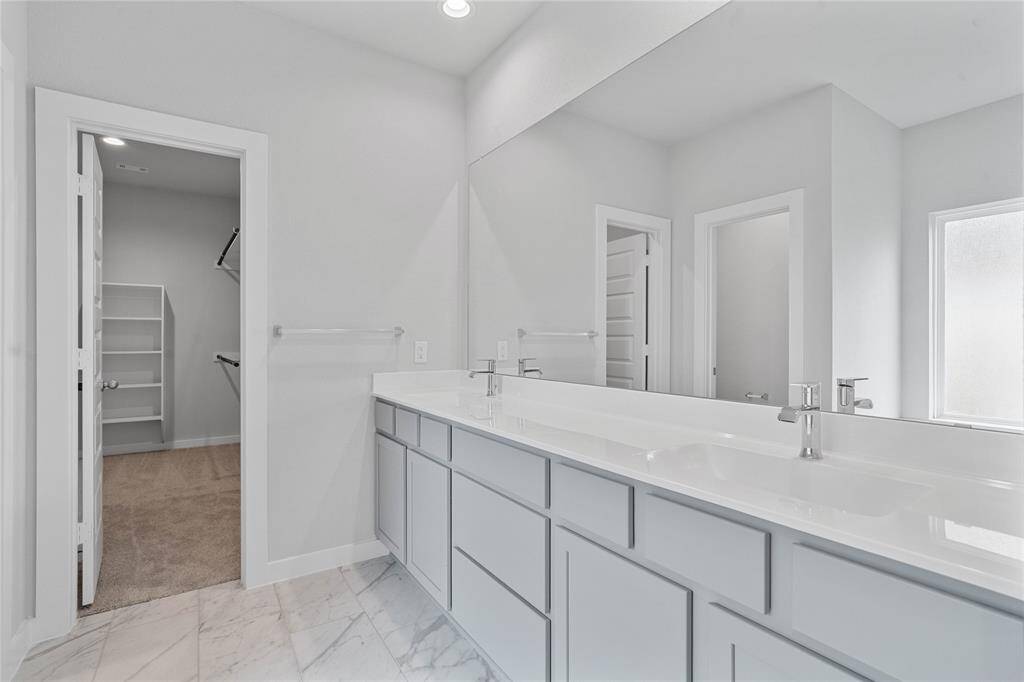 This primary bathroom is definitely move-in ready! Featuring stained cabinets with dual vanities, light countertops, spacious walk-in closet with shelving, high ceilings, custom paint, sleek modern finishes.
