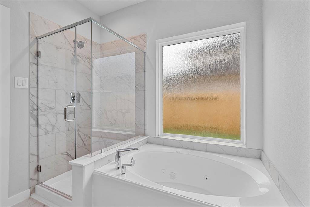 Additional view of the primary bathroom featuring a framed walk-in shower with tile surround and separate garden tub for soaking after a long day!