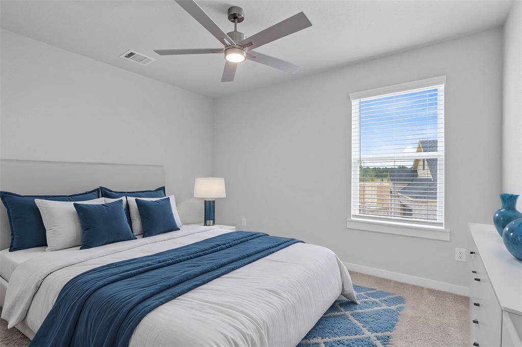 Secondary bedroom features plush carpet, custom paint, high ceilings, ample closet space, and large windows with privacy blinds.