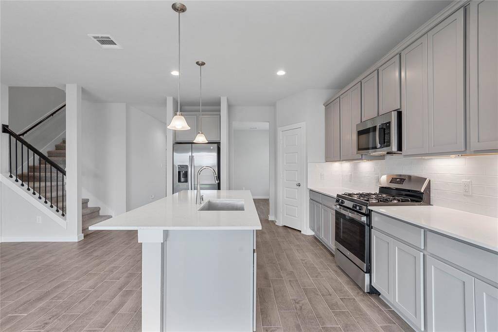 This kitchen is by far any chef’s dream! This spacious kitchen features high ceilings, stained wood cabinets, quartz countertops, SS appliances, modern tile backsplash, recessed and pendant lighting, extended counter space for breakfast bar, and a walk-in pantry all overlooking your huge family room.