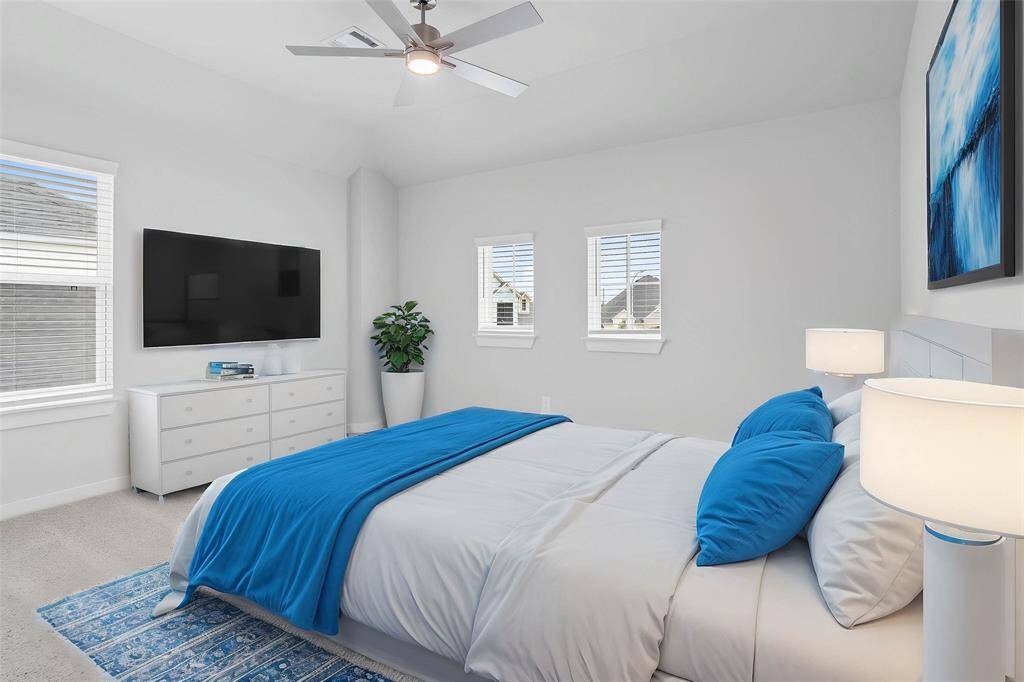 Secondary bedroom features plush carpet, custom paint, ceiling fan, closet space, and large windows with privacy blinds.