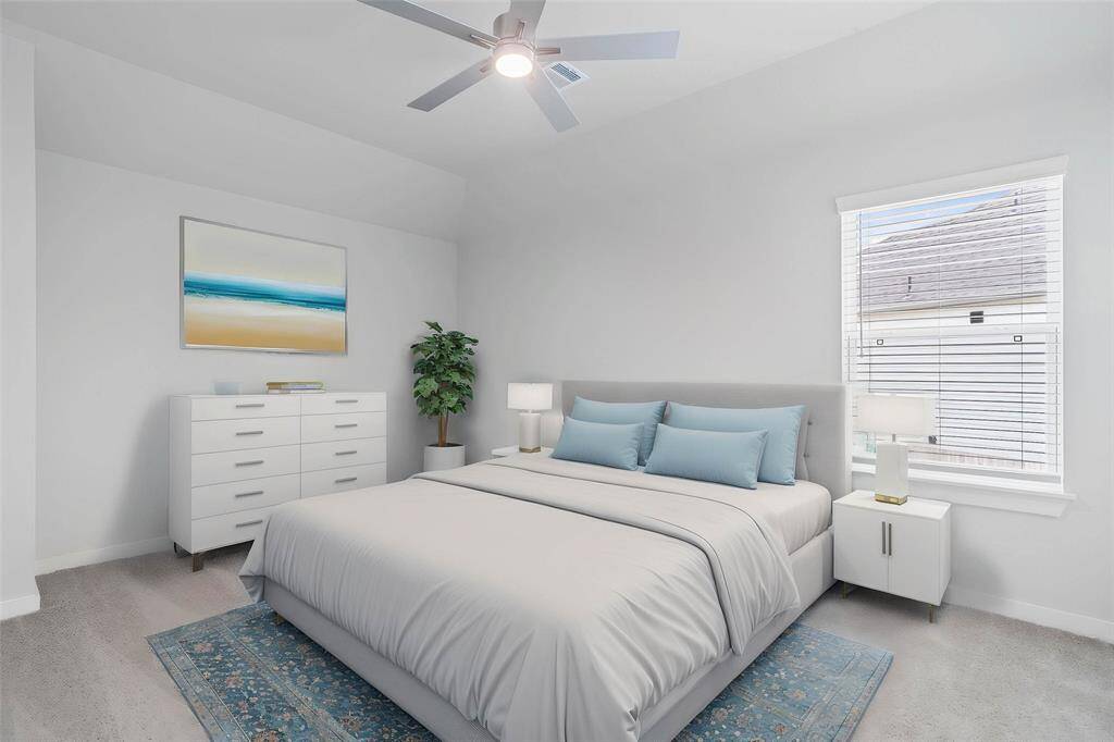 Secondary bedroom features plush carpet, custom paint, ceiling fan, closet space, and a large window with privacy blinds.