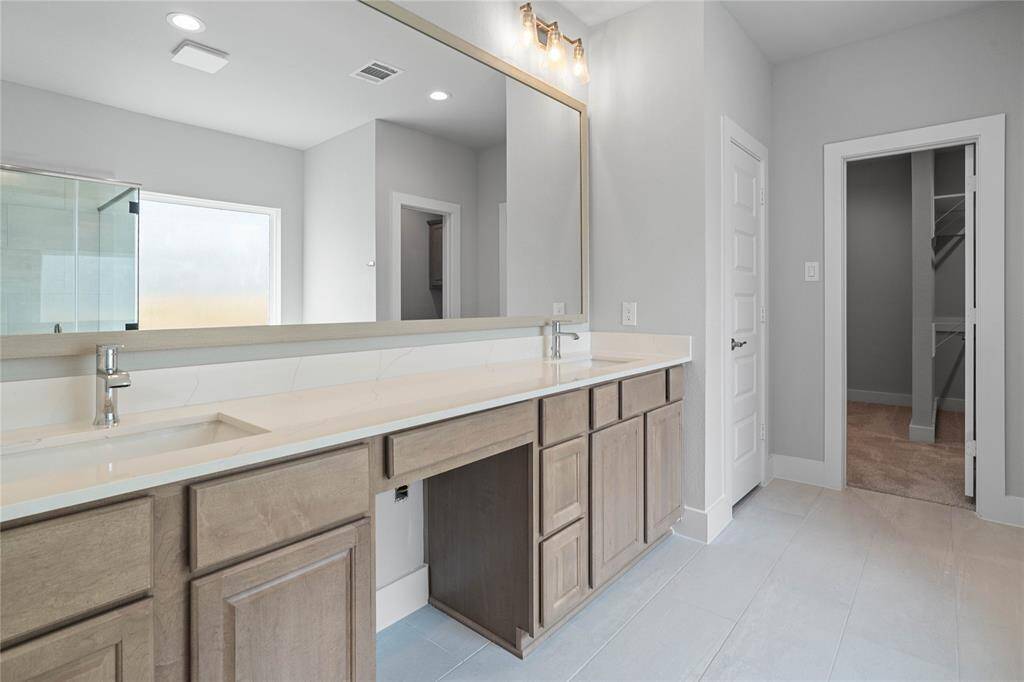 This primary bathroom is definitely move-in ready! Featuring stained wood cabinets with light countertops and dual sinks, spacious walk-in closet with shelving, high ceilings, custom paint, sleek and dark modern finishes.