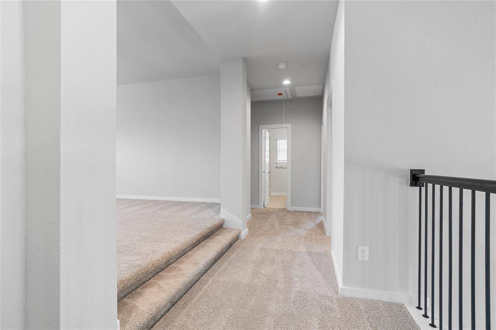 The second floor game room is elevated and is very spacious. Here is a view of the second floor looking at the game room, secondary bathroom, and hallway leading to secondary bedrooms.