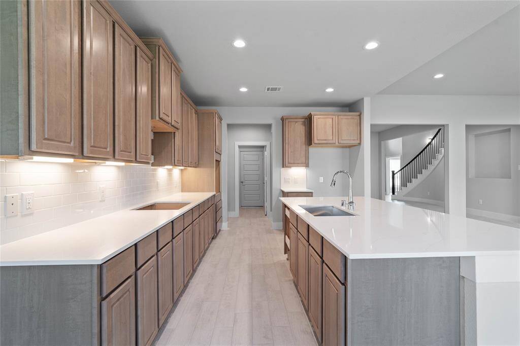 This kitchen is by far any chef’s dream! This spacious kitchen features high ceilings, recessed lighting, stained wood cabinets, quartz countertops, modern tile backsplash, extended counter space, quartz kitchen island with space for breakfast bar, and a walk-in pantry all overlooking your huge family room.