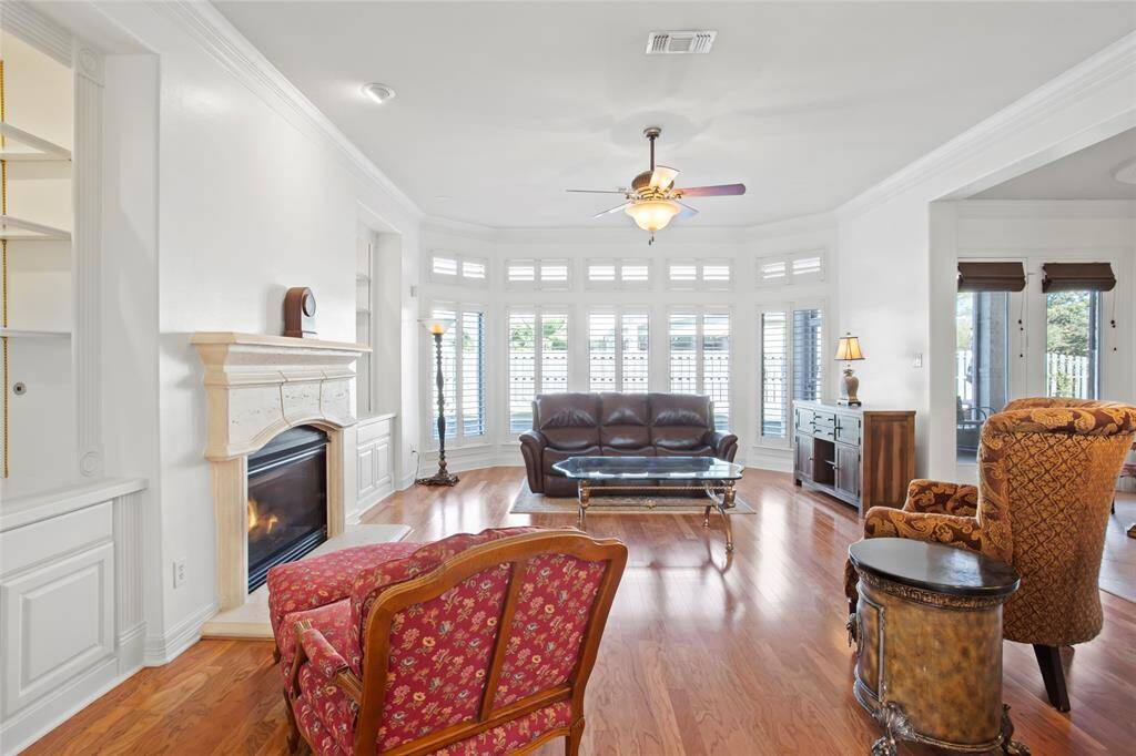 This spacious living room features a cozy fireplace, hardwood floors, and ample natural light from large windows. This is an open concept with a large kitchen and breakfast area to your right.