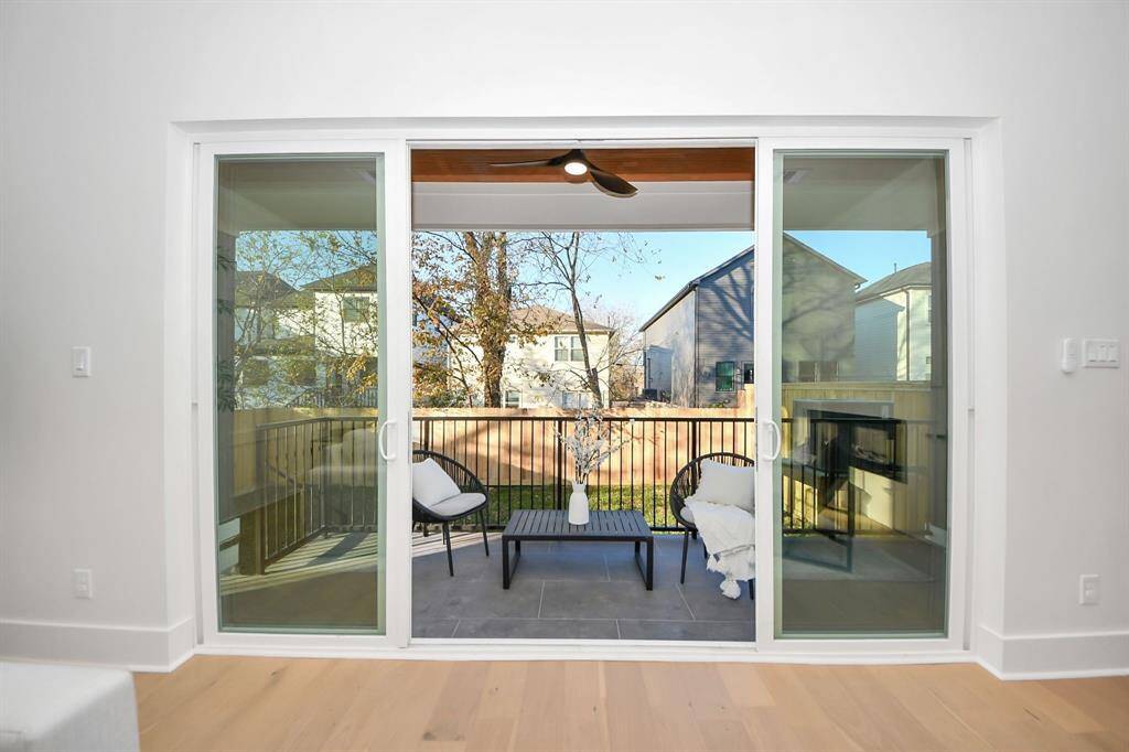 The sliding door opens wide, inviting you onto the waterproofed patio, where sleek metal rails frame the space, and a cedar ceiling with two lights and an exterior fan create a stylish and comfortable outdoor retreat.