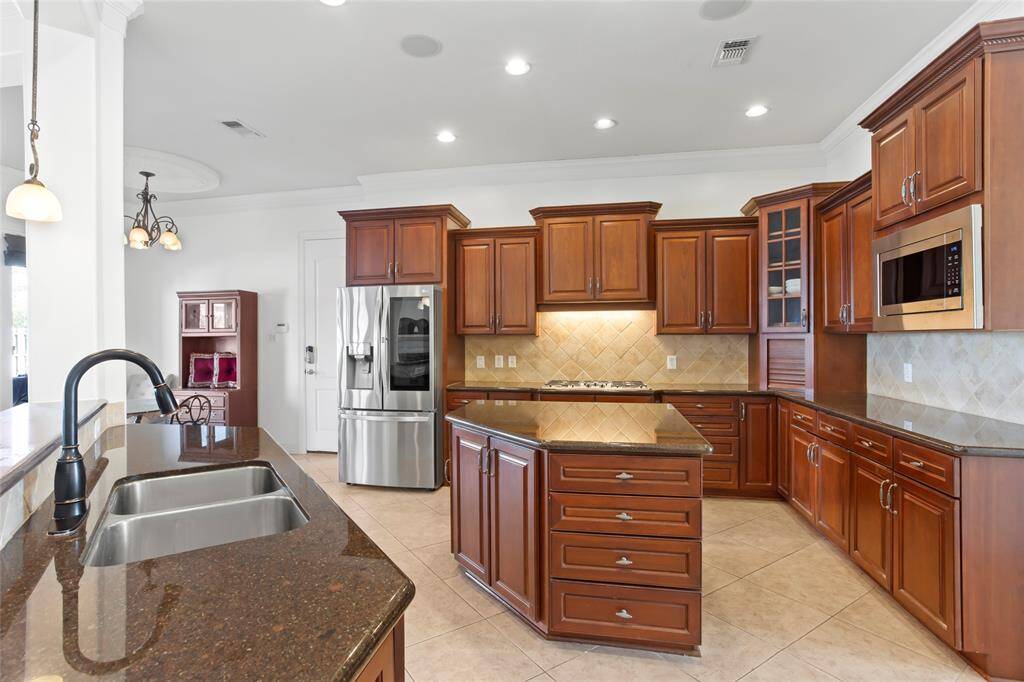 This kitchen features elegant wood cabinetry, granite countertops, a central island, and stainless steel appliances (new LG Refrigerator and LG Microwave). It’s spacious and well-lit, offering a modern and functional cooking space.