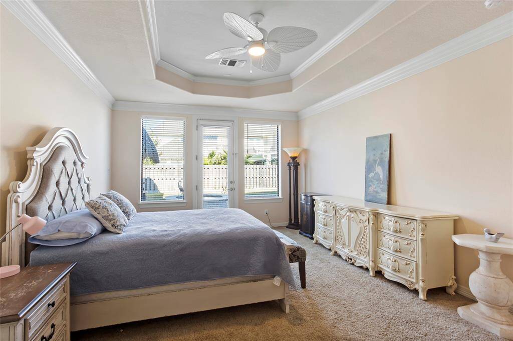 This primary bedroom is spacious and bright and has it's own entrance to the pool and spa area. It has multiple bay windows that let in natural light and includes an elegant tray ceiling with a fan.