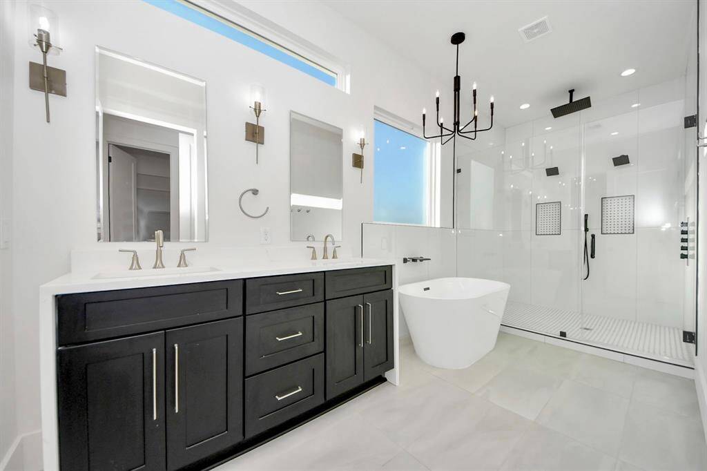 Elegance flows throughout the sleek bathroom, centered around the impressive waterfall double vanity— a rare and striking feature that’s enhanced by the rich black cabinetry.
