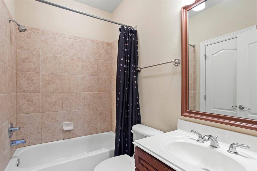 This bathroom features a tiled shower and bathtub combination, a modern sink with a sleek faucet, and a large mirror with a wooden frame.