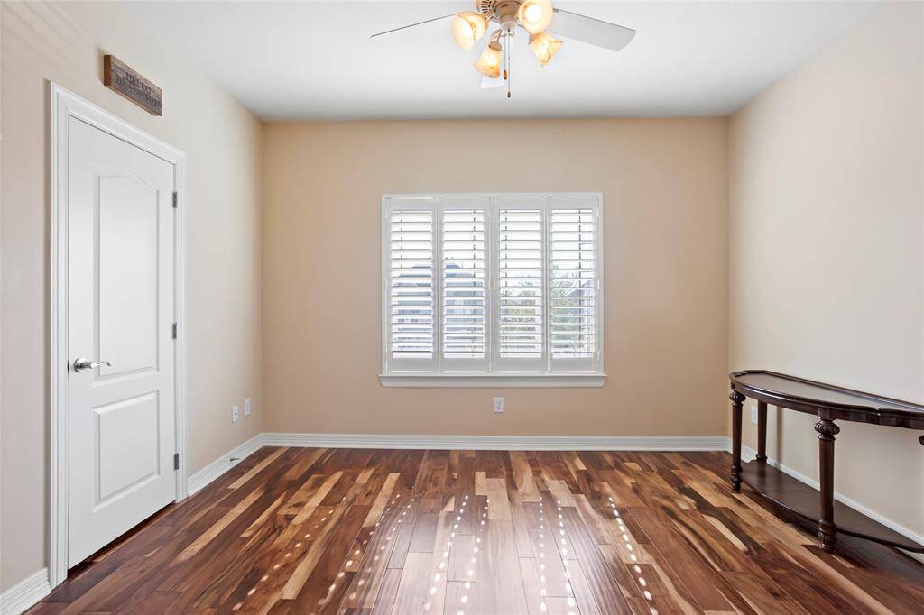 Bright bedroom room with beautiful brazilian hardwood floors, neutral walls, and a ceiling fan. Features a window with plantation shutters. Large walk in closet.