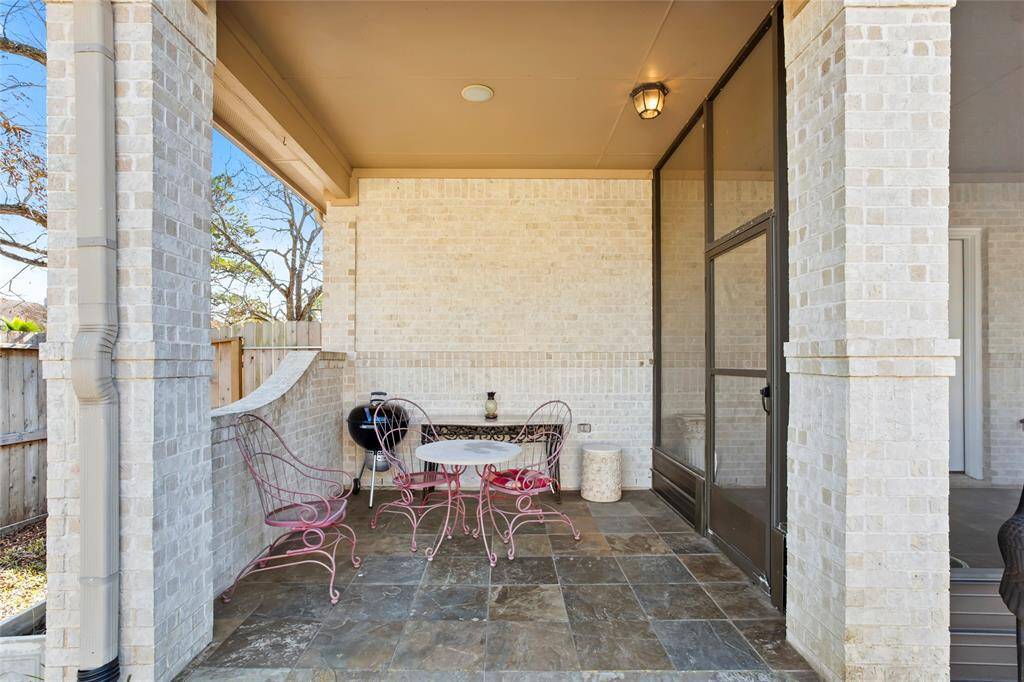 This charming outdoor patio features light brick walls, slate tile flooring, and a cozy seating area perfect for relaxing or entertaining.