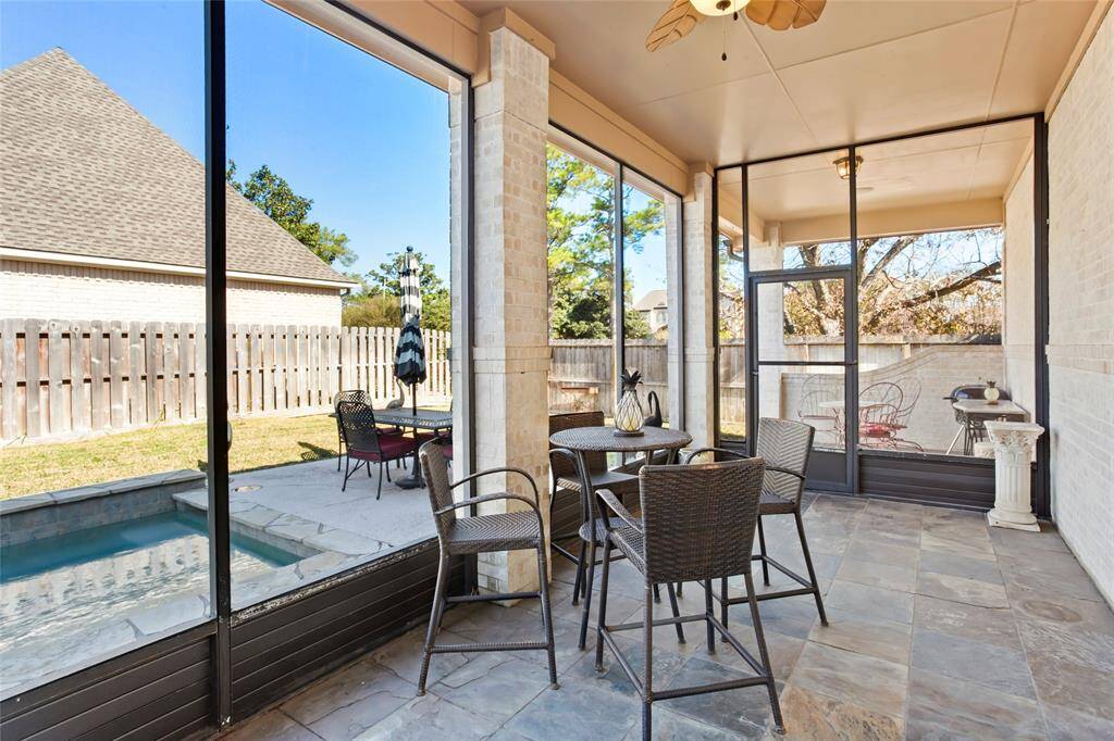 Large screened-in patio with a ceiling fan and tiled floor, offering a cozy outdoor dining area. Beyond the patio, there's a small covered dining area that leads to the pool.