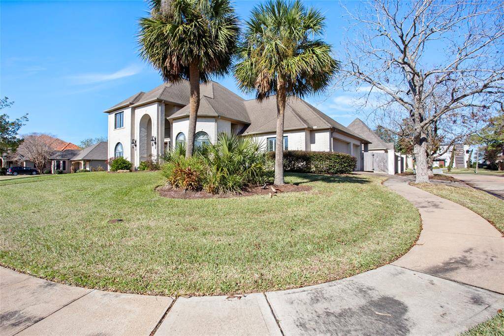 This is a spacious two-story home with a well-maintained lawn, featuring palm trees and a curved walkway. The exterior showcases a blend of modern and classic architecture with large windows and a sloped roof. Ideal for families looking for a stylish suburban residence.