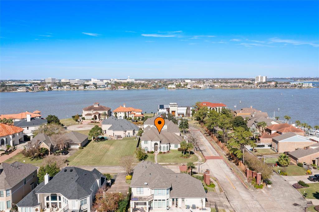 This aerial photo showcases a beautiful waterfront neighborhood with spacious homes and well-maintained lawns. The highlighted property is positioned near the water, offering scenic views and access to ample outdoor activities. The area is tranquil and upscale, ideal for those seeking a serene living environment.
