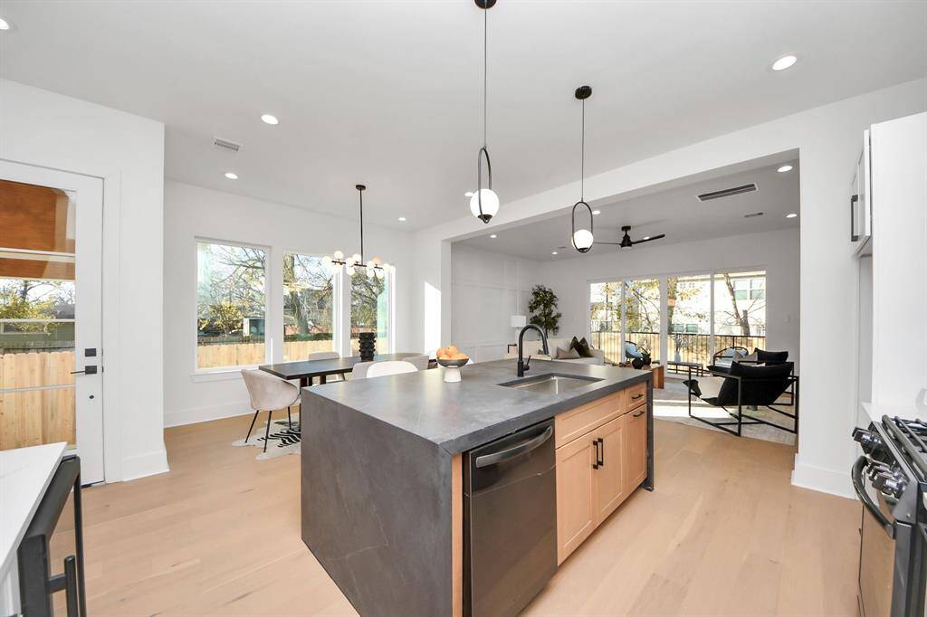 The large island adds warmth to the home, complemented by wood-style cabinets and a striking black island as a contract. The spacious sink is paired with a sleek kitchen faucet, enhancing the modern aesthetic. The top-control built-in dishwasher offers a quiet cleaning experience, thanks to its advanced insulation system, which significantly reduces or eliminates noise from the 3 spray arms.